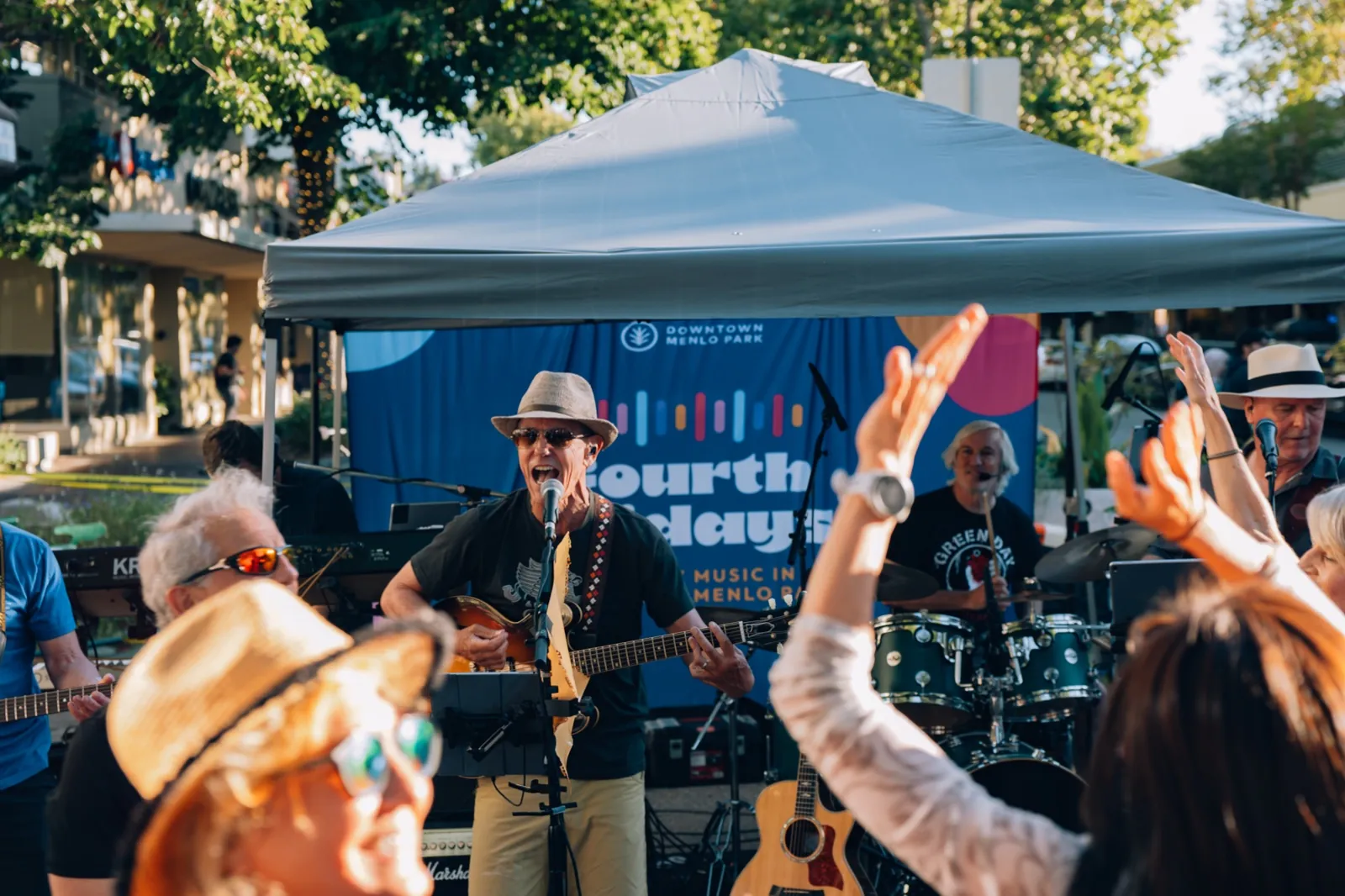 A band plays under the Fourth Fridays banner as the crowd dances in golden-hour light